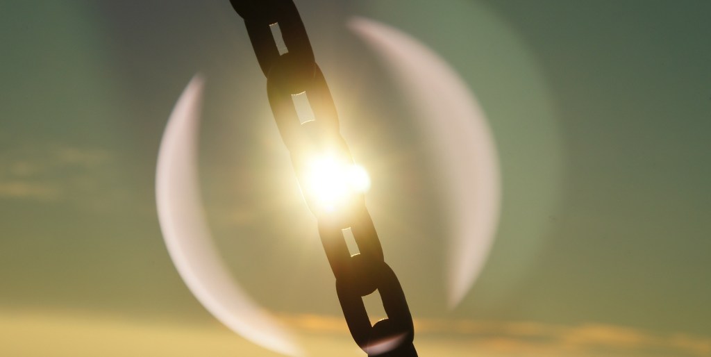 Poetry, chain links against the bright sun with its fire glow burning through a link