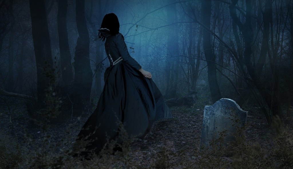Poetry The back of a woman dressed in medieval midnight frock walking in a graveyard with a headstone jutting out from the ground in backdrop of a dark forest