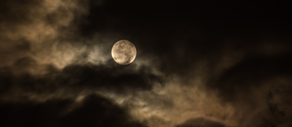 Poetry White shining full moon disc on a dark cloudy night sky