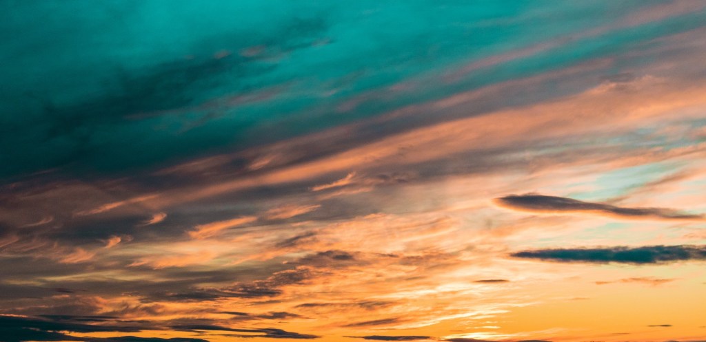 Poetry sunset horizon with the sky painted blue, orange and yellow.