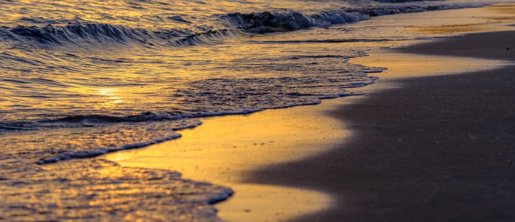 Poetry sea waves in sunset waving into the sands of the beach