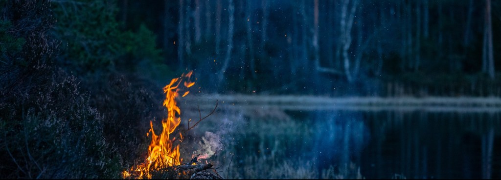 Poem A campfire by the lake in the night surrounded by trees